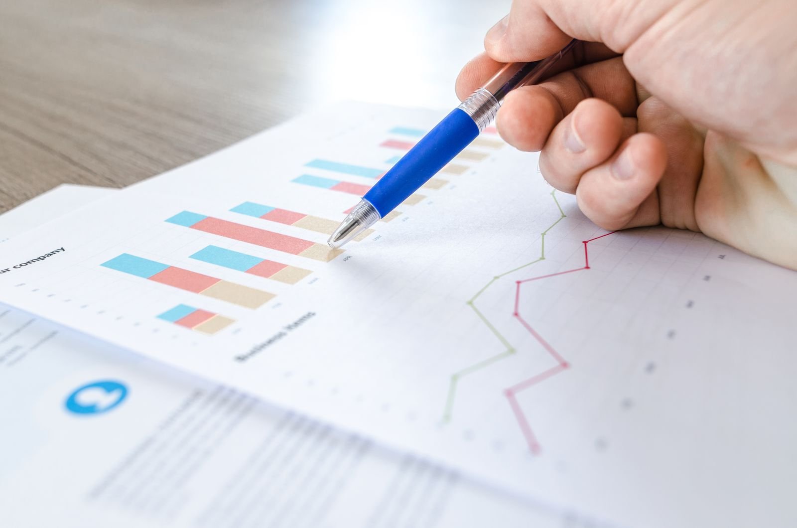 Hand pointing a pen at business charts and graphs